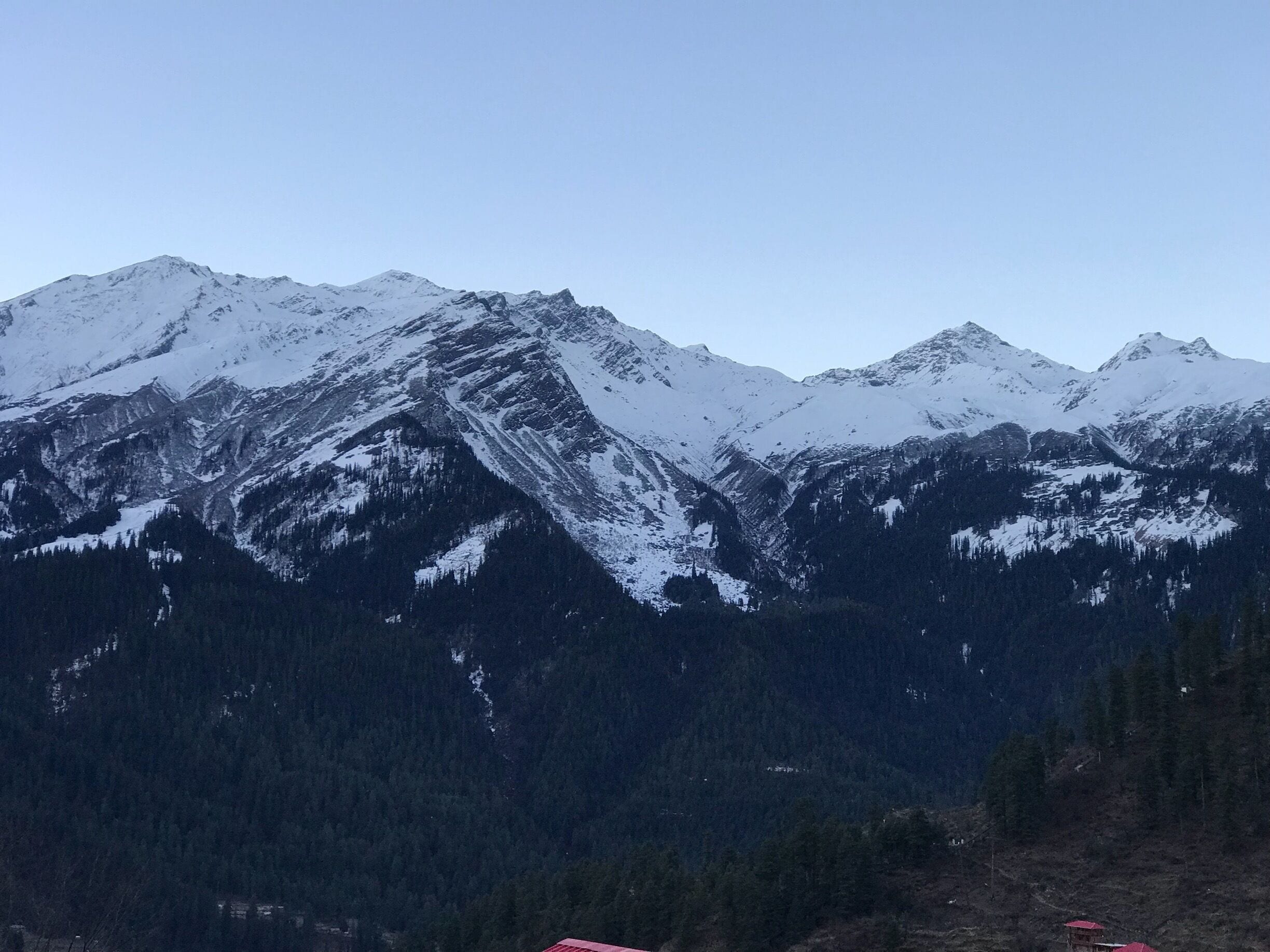Snow-covered mountains, dense forests, and a few red-roofed buildings.