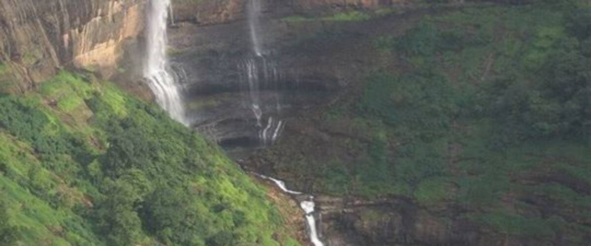 A waterfall cascading down a steep cliff surrounded by lush green vegetation.