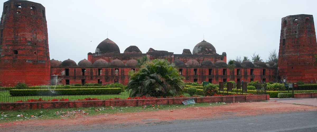 A large, red brick building with multiple domes and two tall towers.