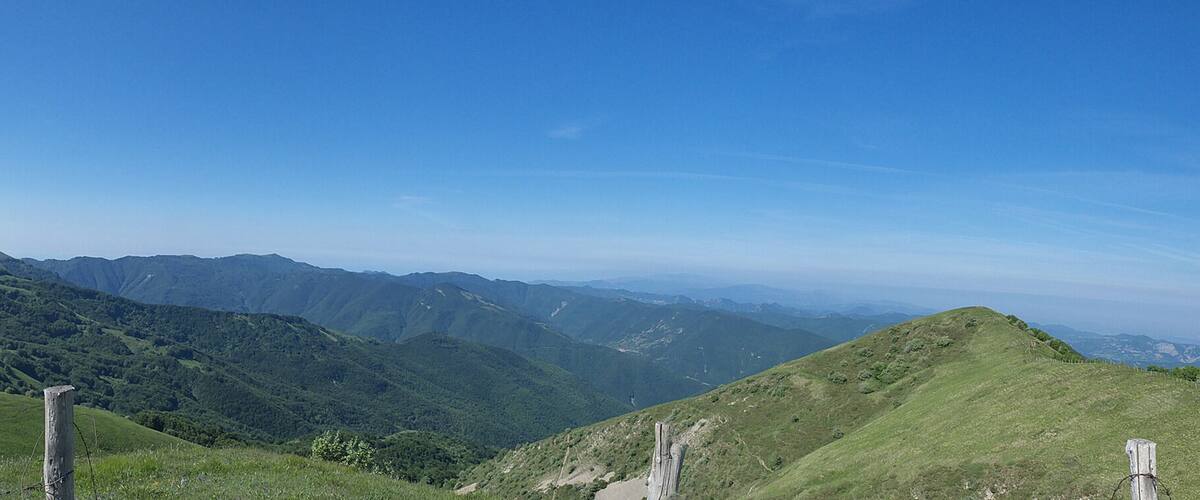 A mountainous landscape with green hills and a clear blue sky.