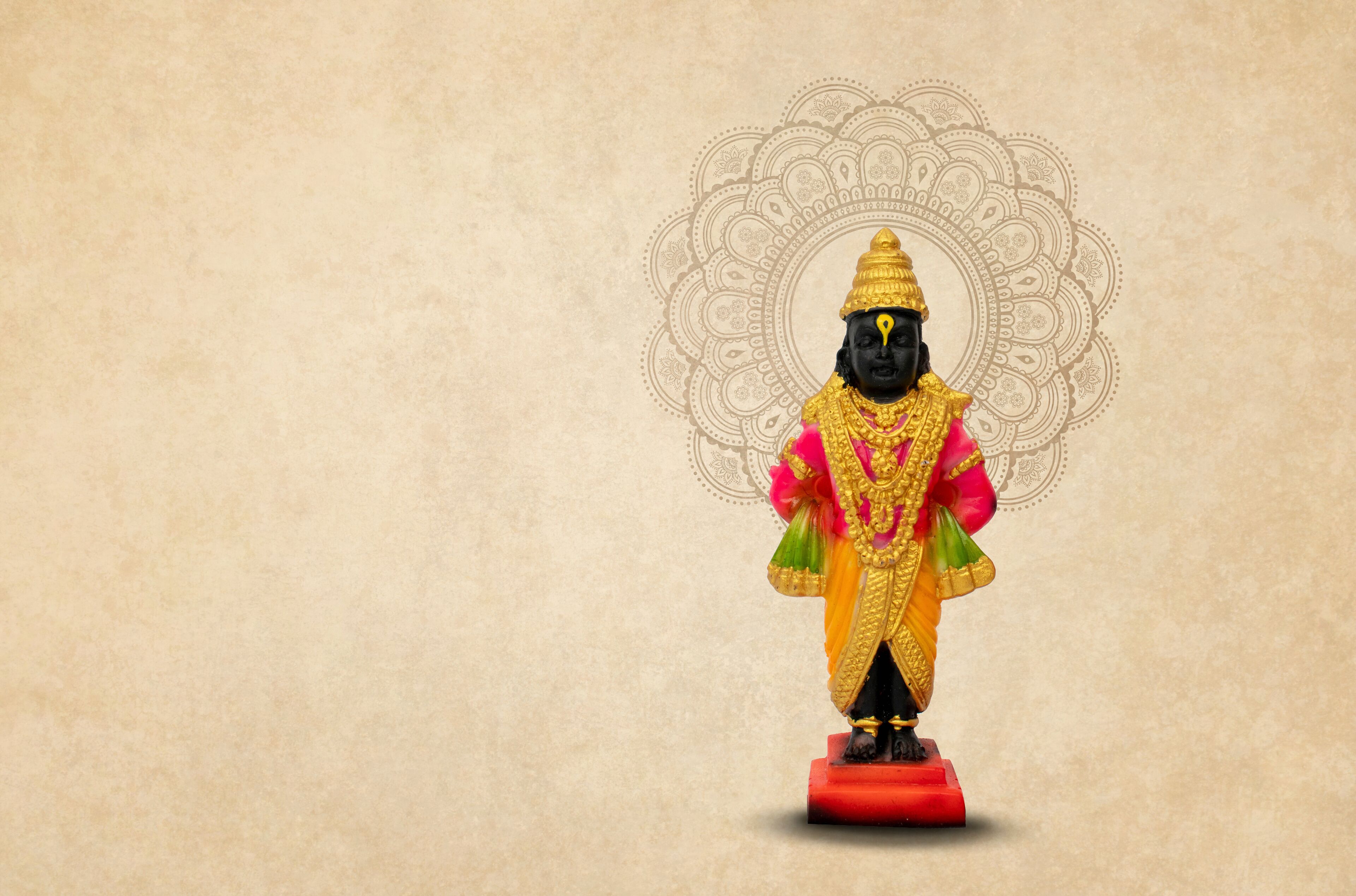 A statue of a deity with a golden headdress and a red base.