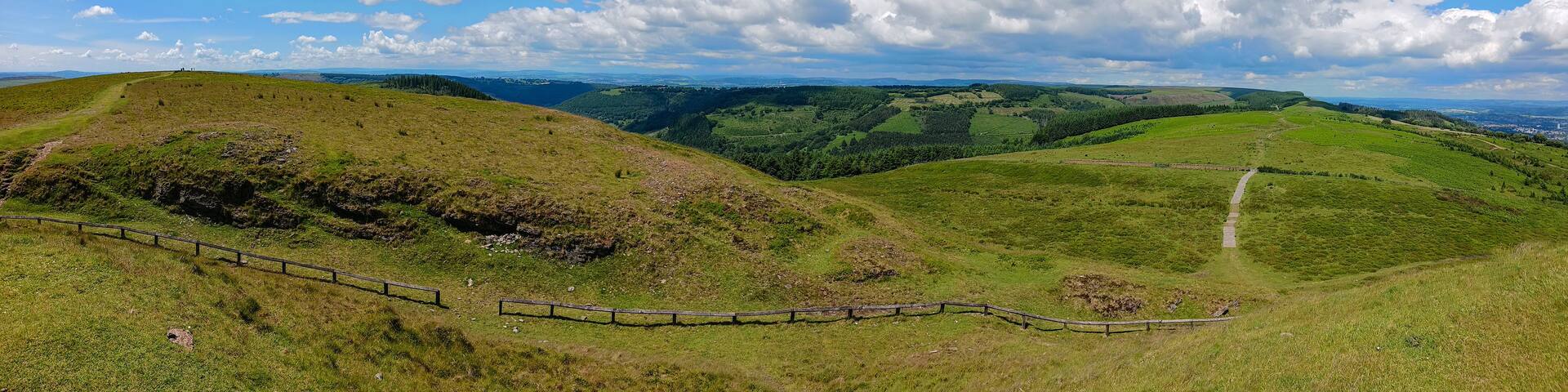 Rolling hills, a fenced path, and a distant town.