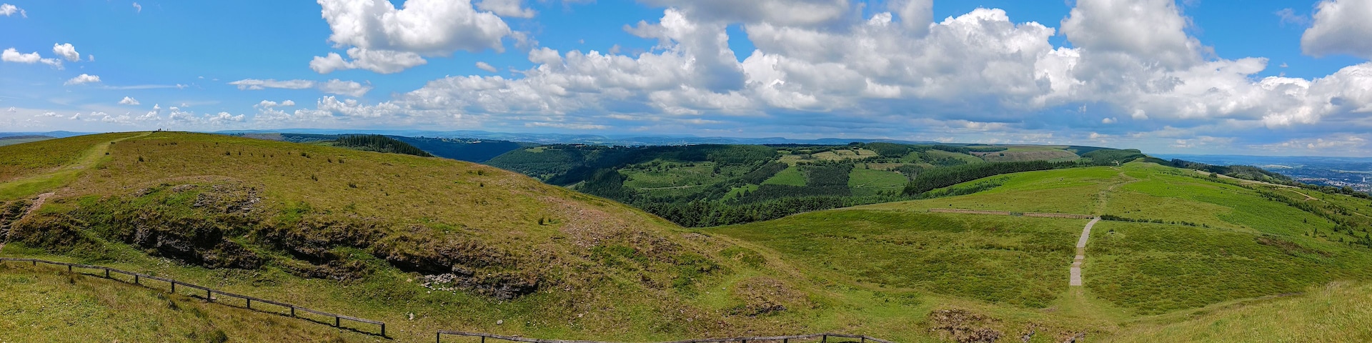 Colinas ondulantes, un sendero cercado y un pueblo lejano.