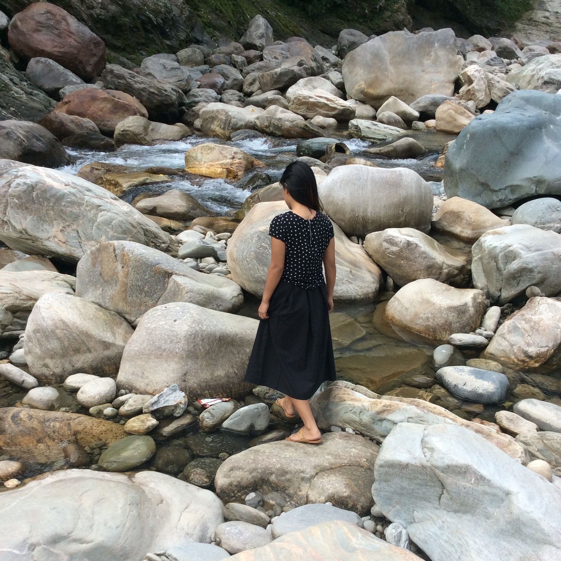 Una persona de pie sobre rocas cerca de un arroyo.