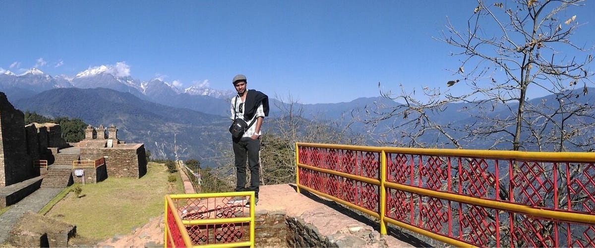 A historical site with ruins and a mountainous backdrop.