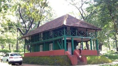 Un edificio verde y rojo con techo de tejas, rodeado de árboles y un sendero de piedra.