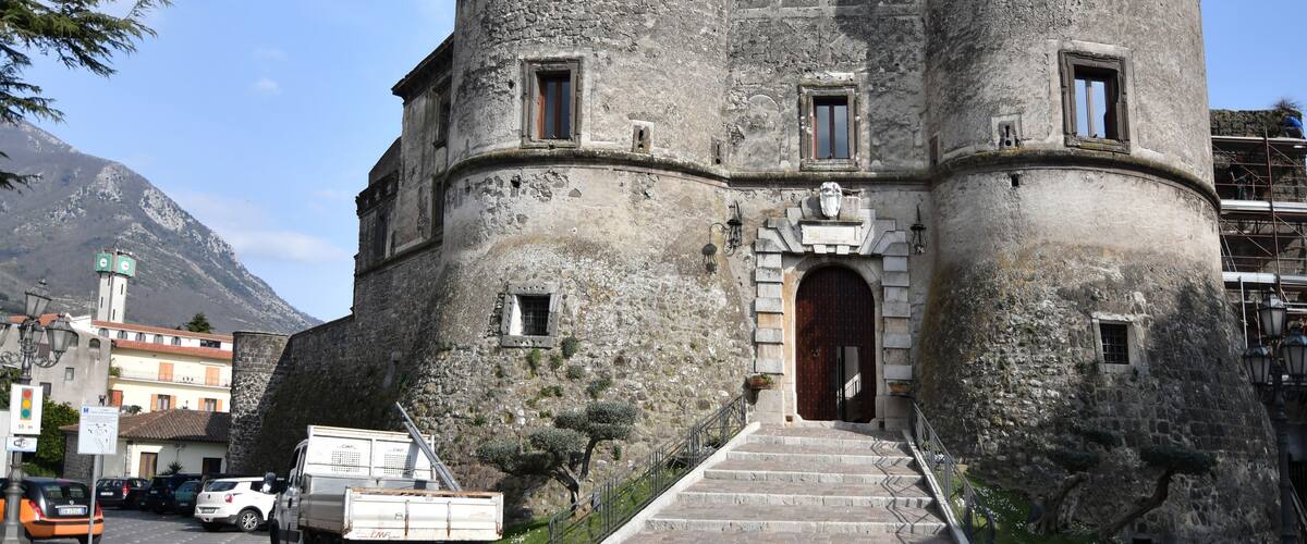 A historic stone building with a rounded tower, a wooden door, and a staircase leading to the entrance.