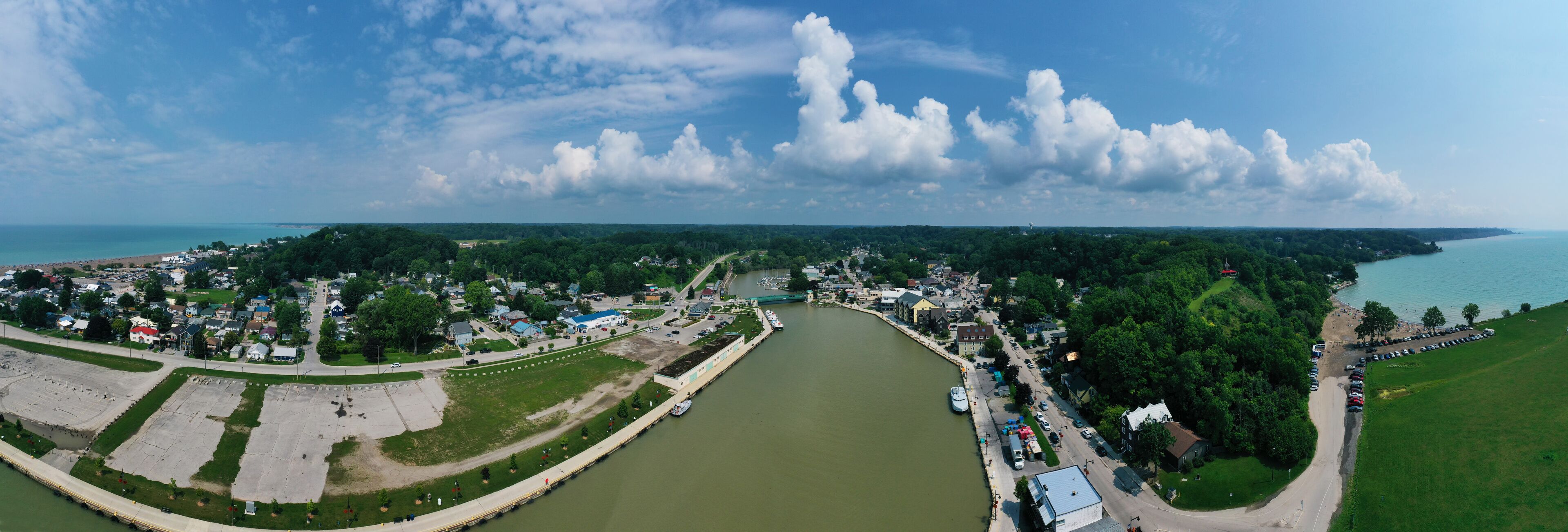A river winding through a town with a bridge, surrounded by greenery and buildings.
