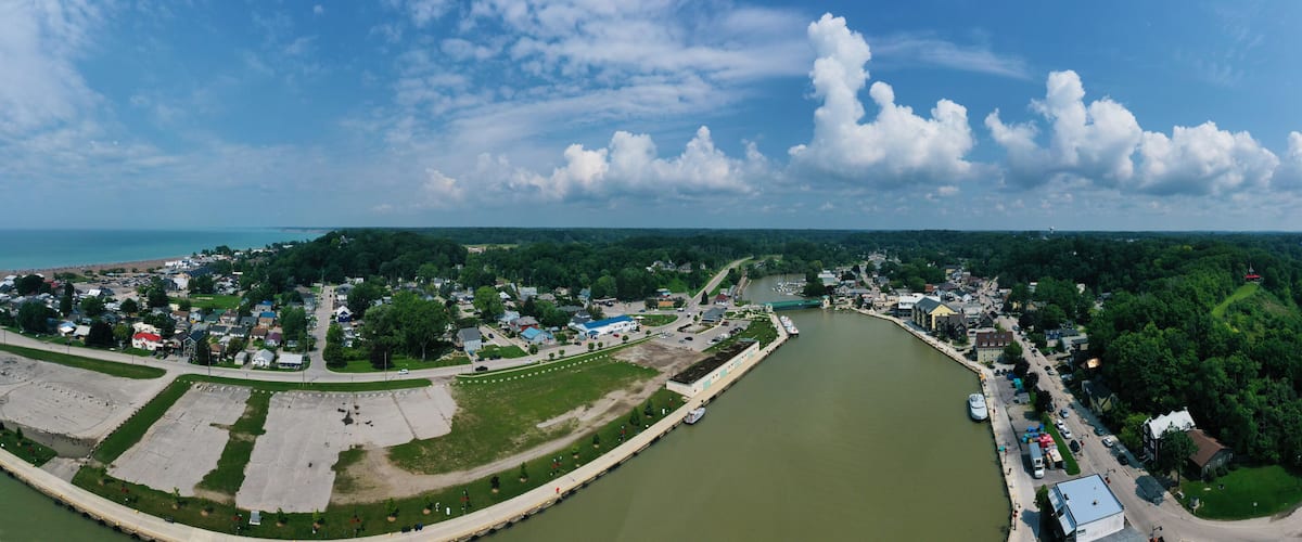 A river winding through a town with a bridge, surrounded by greenery and buildings.