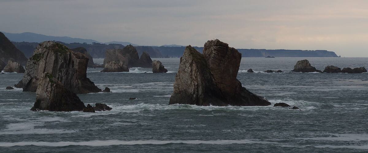 A coastal landscape with prominent rock formations emerging from the sea.
