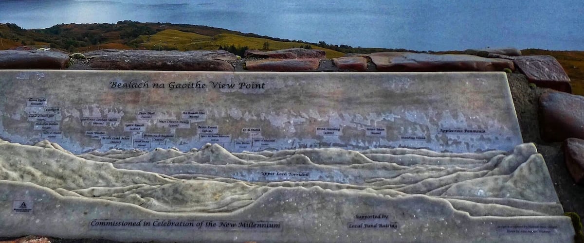 A scenic view of Bealach na Gaoithe View Point with a plaque detailing the landscape.
