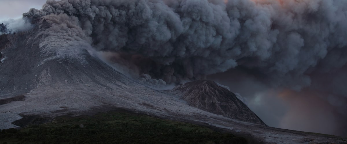 A mountain with a large plume of smoke rising from its peak.