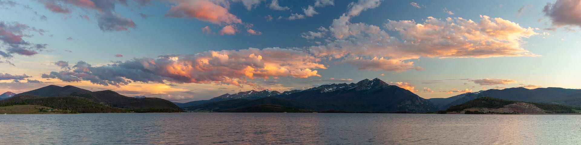A mountainous landscape with a lake and a sunset sky.