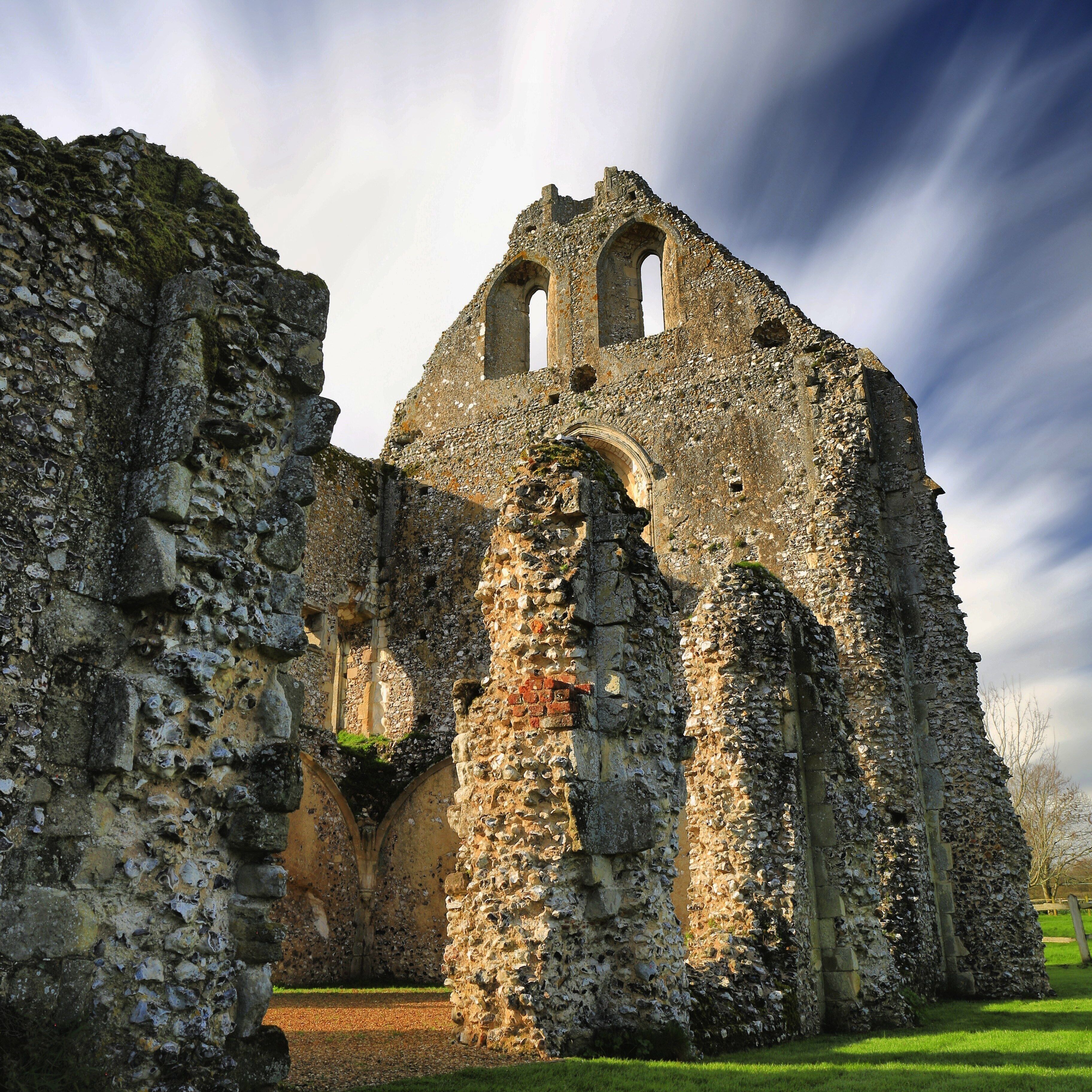 An ancient stone building with arched doorways and a tower.
