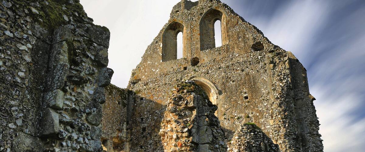 An ancient stone building with arched doorways and a tower.