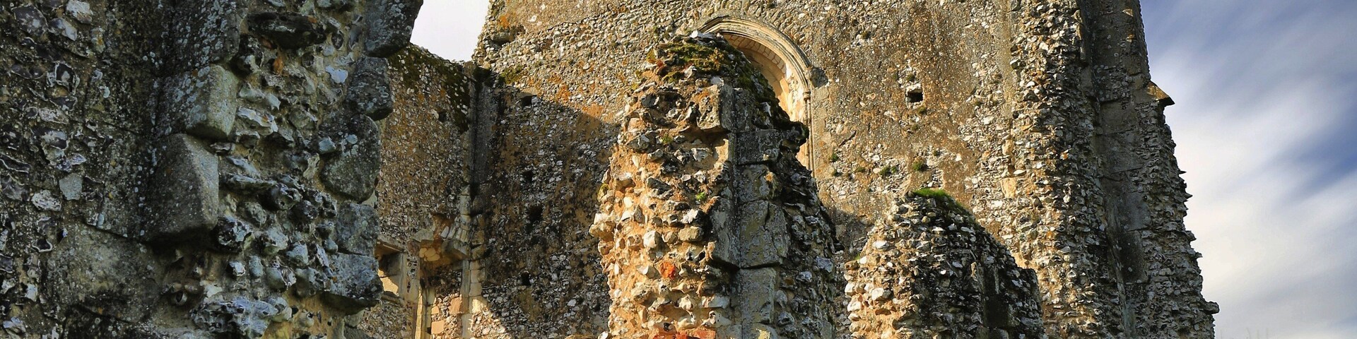 An ancient stone building with arched doorways and a tower.