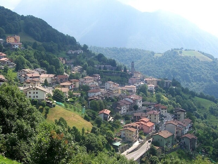 Un pueblo en la ladera con casas escalonadas, una carretera sinuosa y una iglesia.
