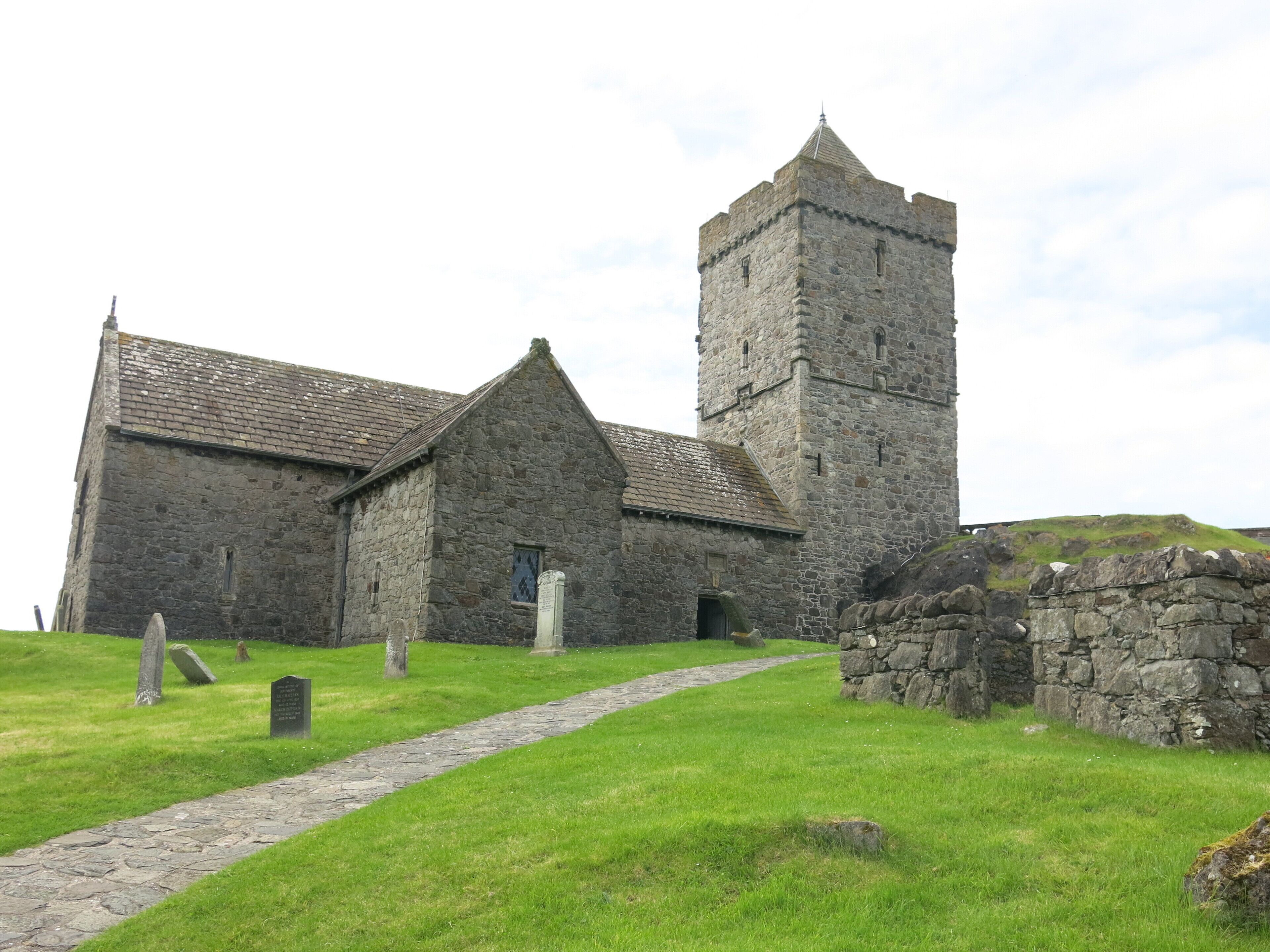A stone church with a tower and a pathway leading to the entrance.