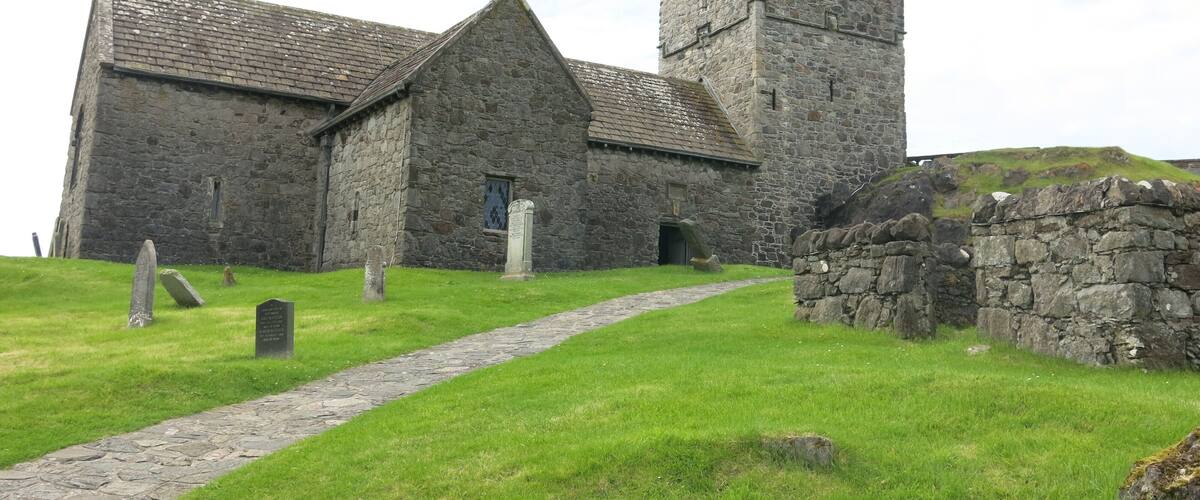 A stone church with a tower and a pathway leading to the entrance.