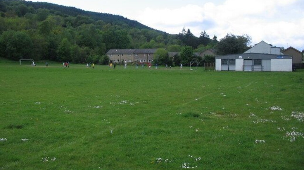 Fitba' in the park. A view looking to the northwest across the playing fields of Howie Park, with a football match in progress. The white building at right is the Princess Louise Memorial Hall, named after a relative of Queen Victoria and an erstwhile resident of Rosneath Castle.