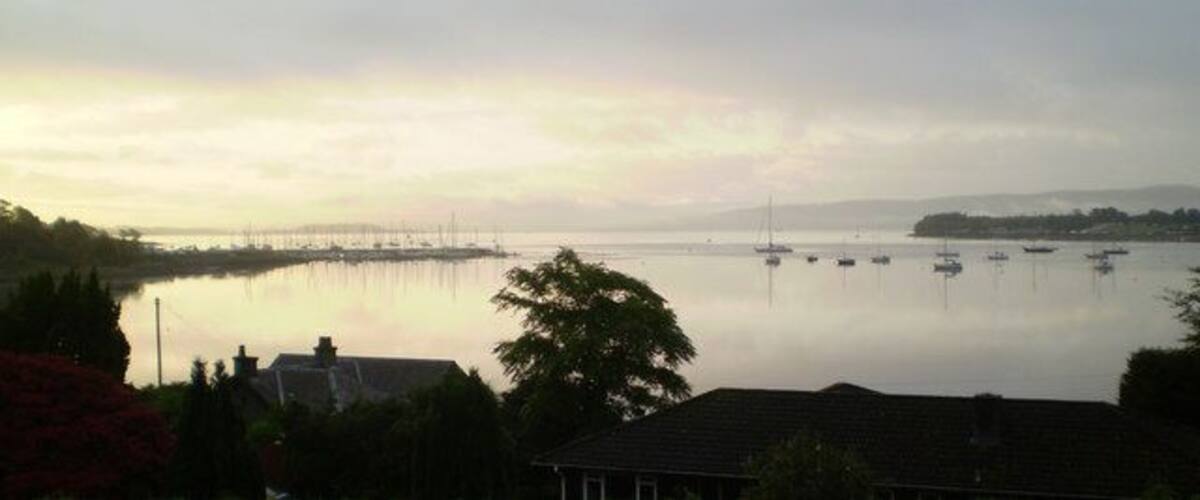 A calm lake with boats, a pier, and houses in the foreground.