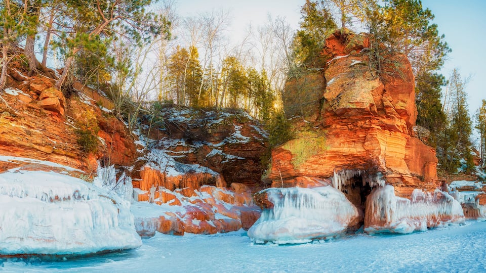A frozen river with ice formations and red rock cliffs.