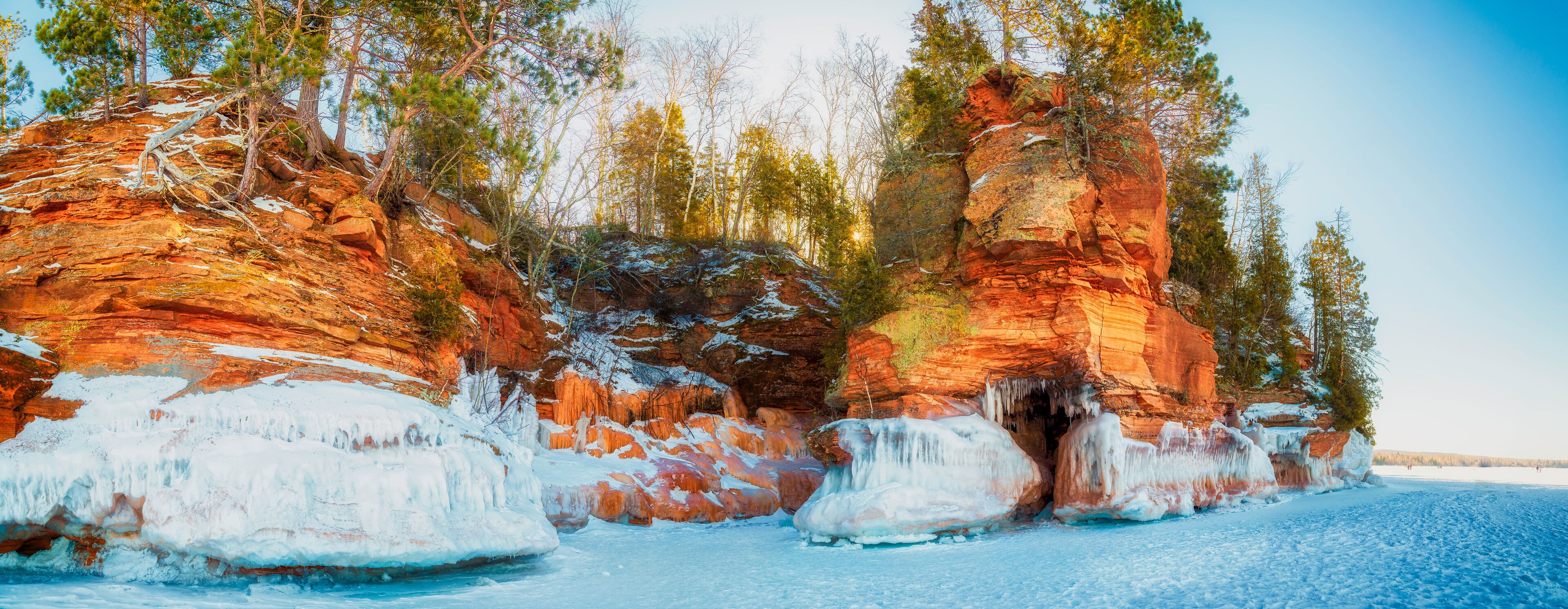 A frozen river with ice formations and red rock cliffs.