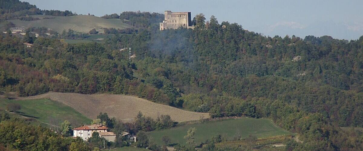 Un castello su una collina, circondato da prati verdi e alberi.
