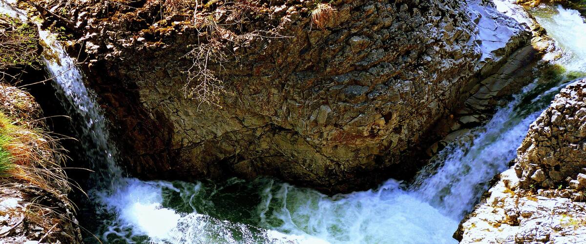 A waterfall cascading into a rocky gorge with sparse vegetation.