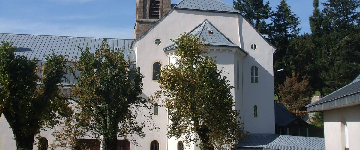 A church with a clock tower, surrounded by trees and other buildings.