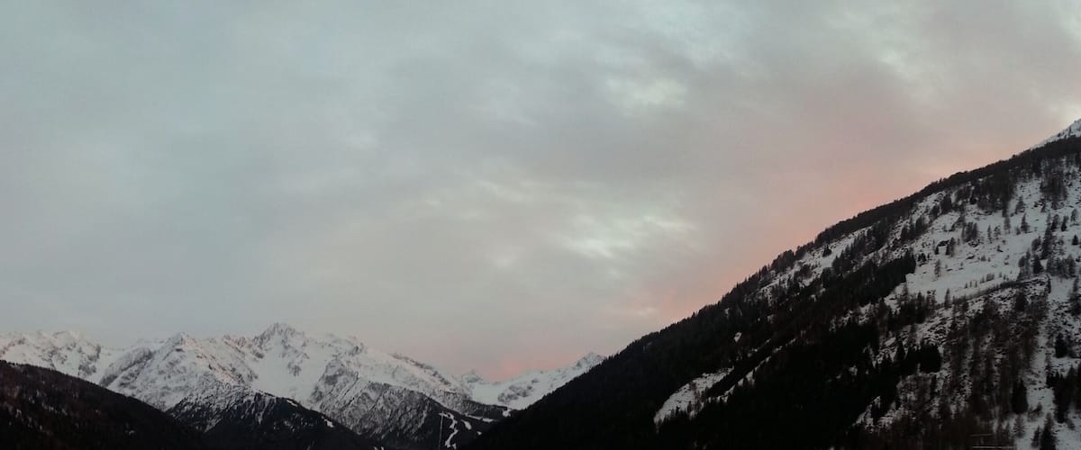 Snow-covered mountains with a cloudy sky.