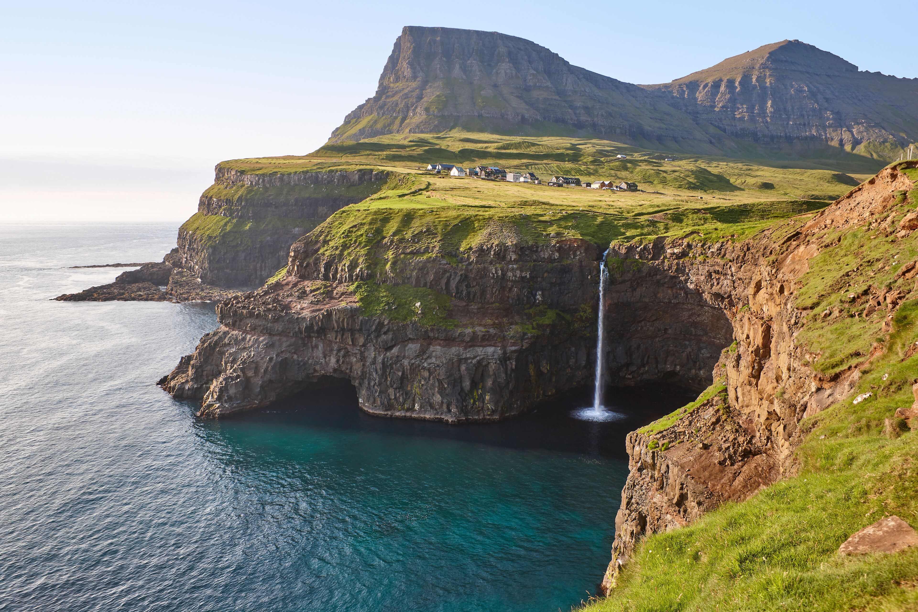 Waterfall and cliffs on Vagar. Faroe Islands coastline. Gasaladur