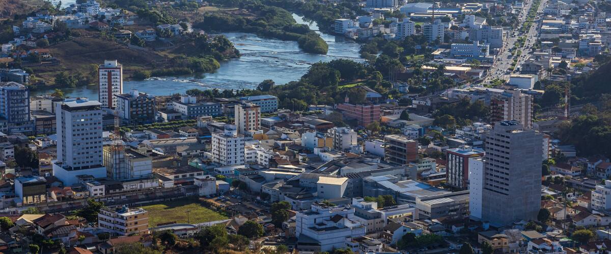 A cityscape with a river, mountains, and a mix of residential and commercial buildings.