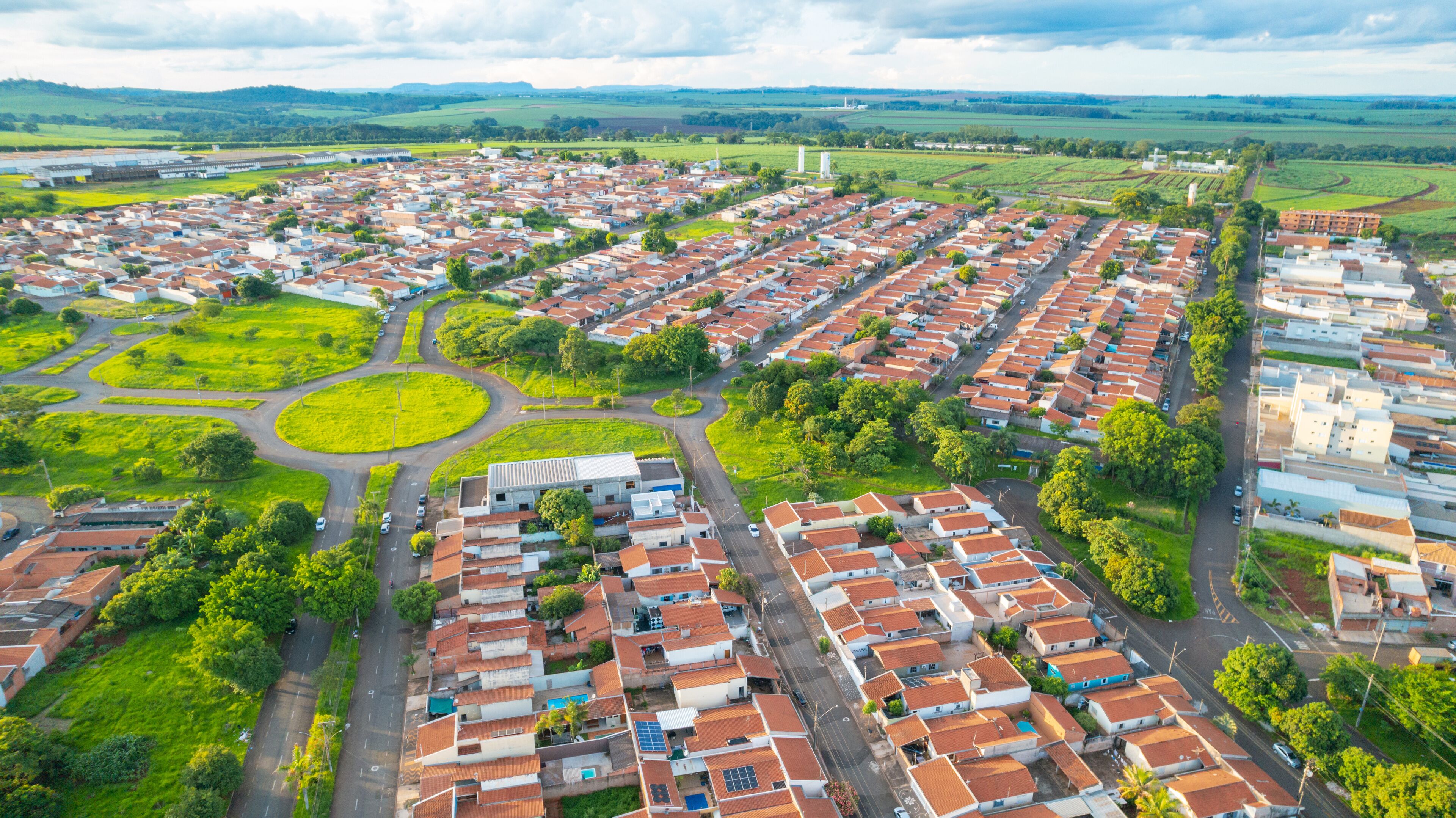 An aerial view of a residential area with houses, roads, and green fields.