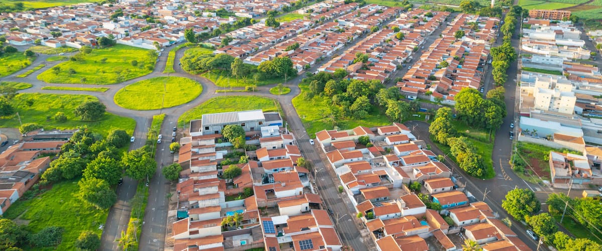An aerial view of a residential area with houses, roads, and green fields.