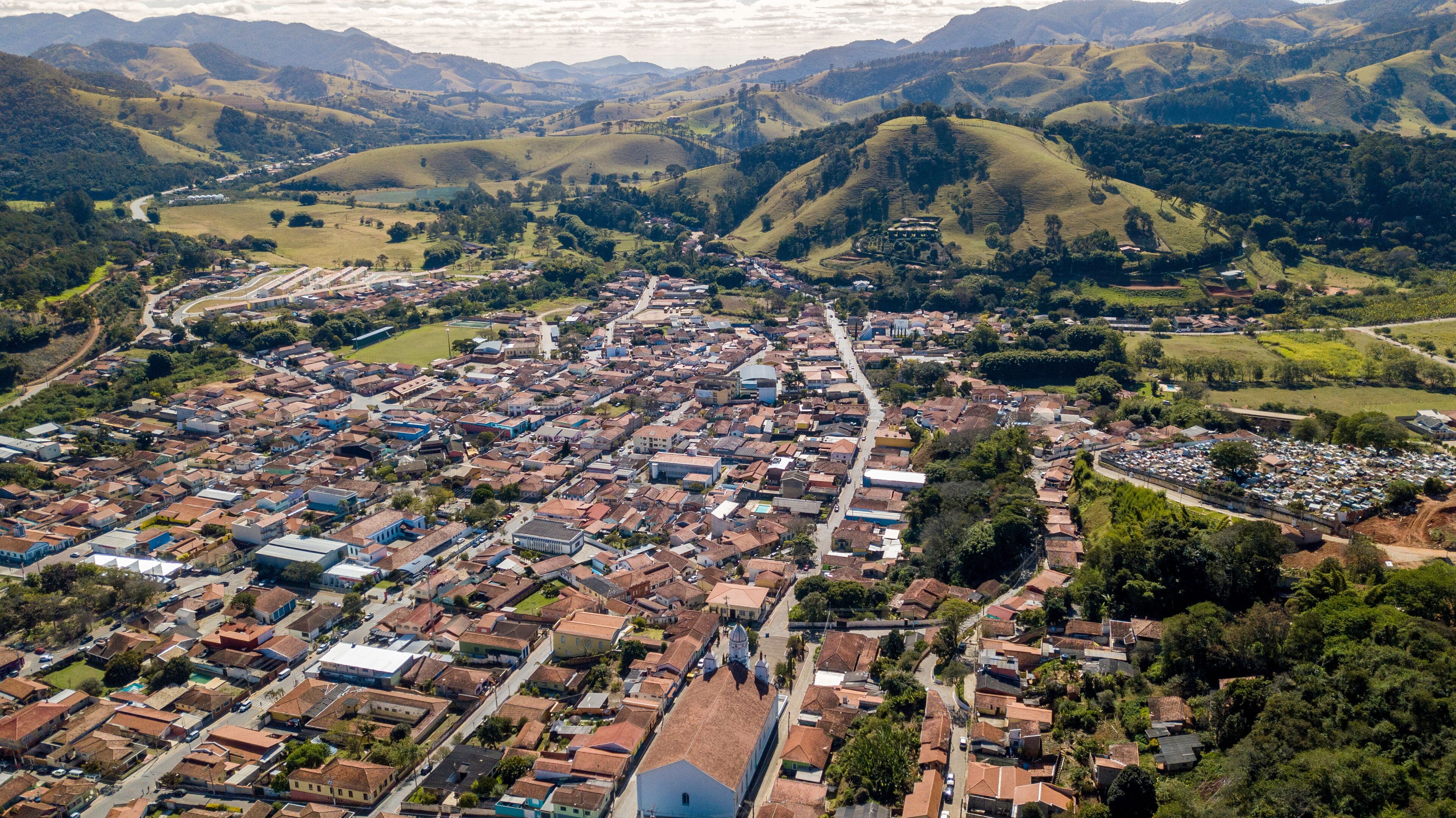 An aerial view of a town with a river running through it, surrounded by rolling hills and mountains.