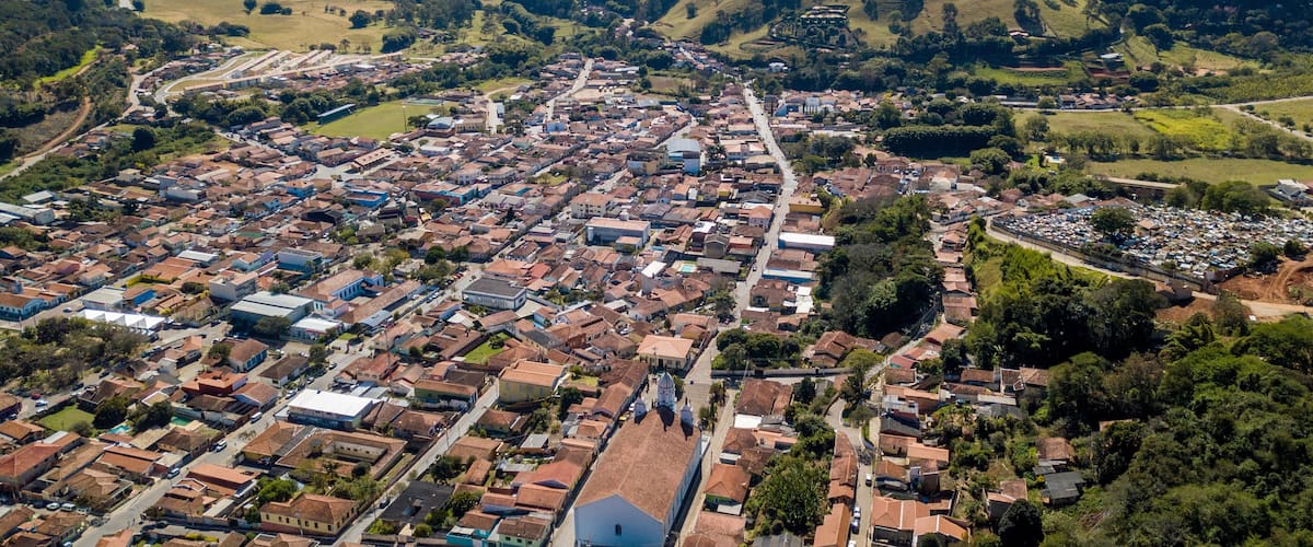 An aerial view of a town with a river running through it, surrounded by rolling hills and mountains.