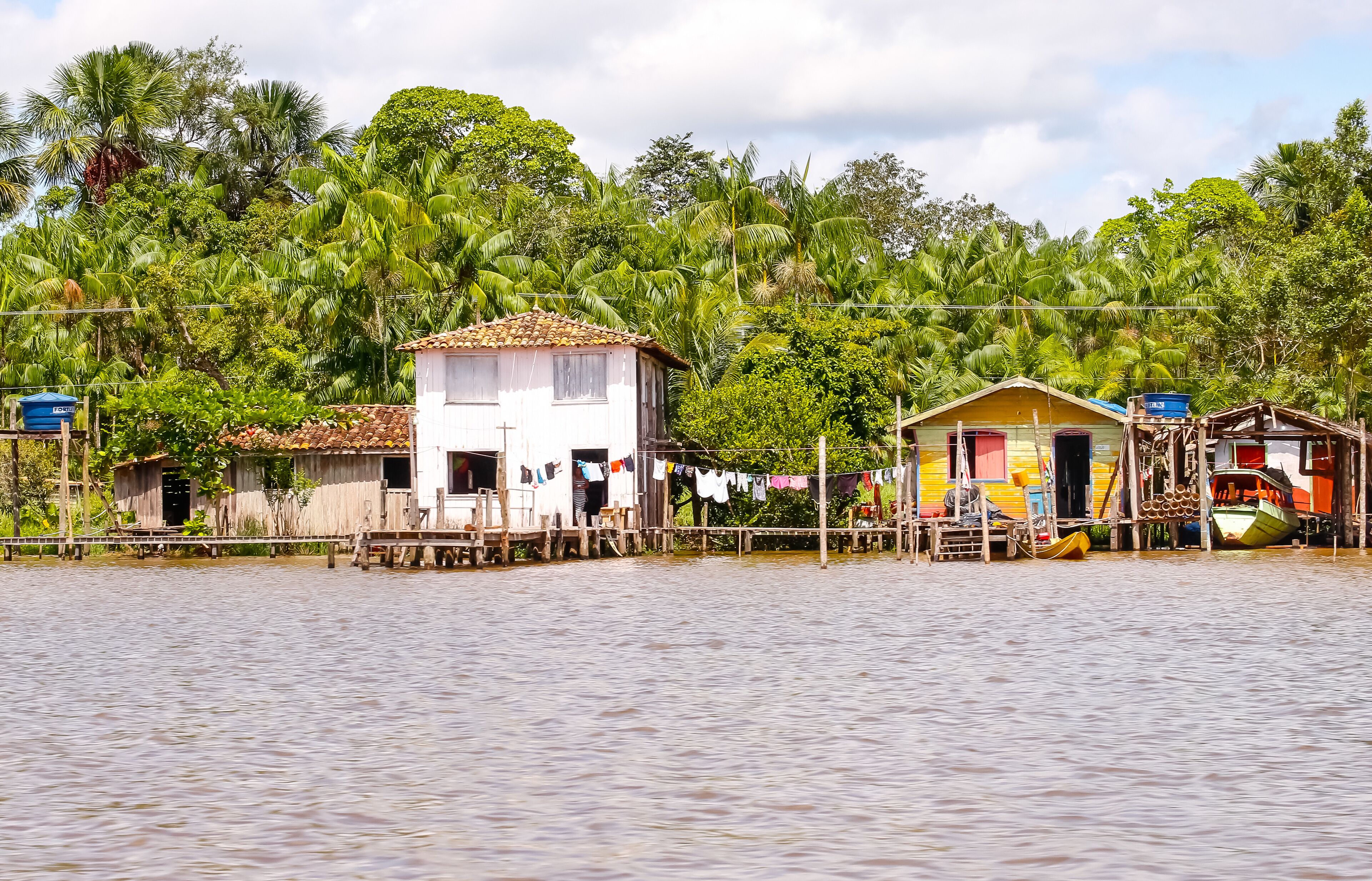A riverside village with wooden houses, a bridge, and lush greenery.