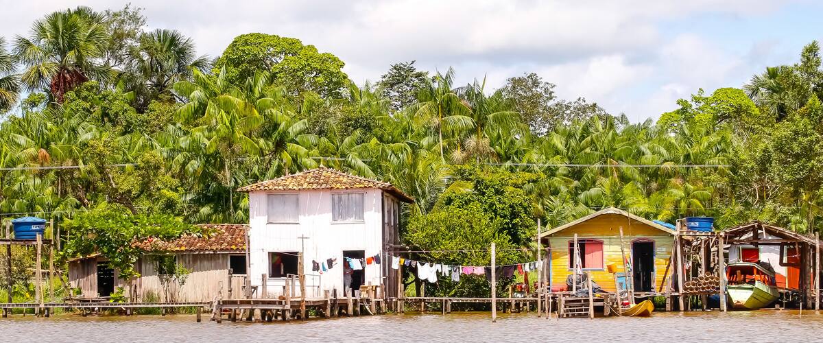 A riverside village with wooden houses, a bridge, and lush greenery.