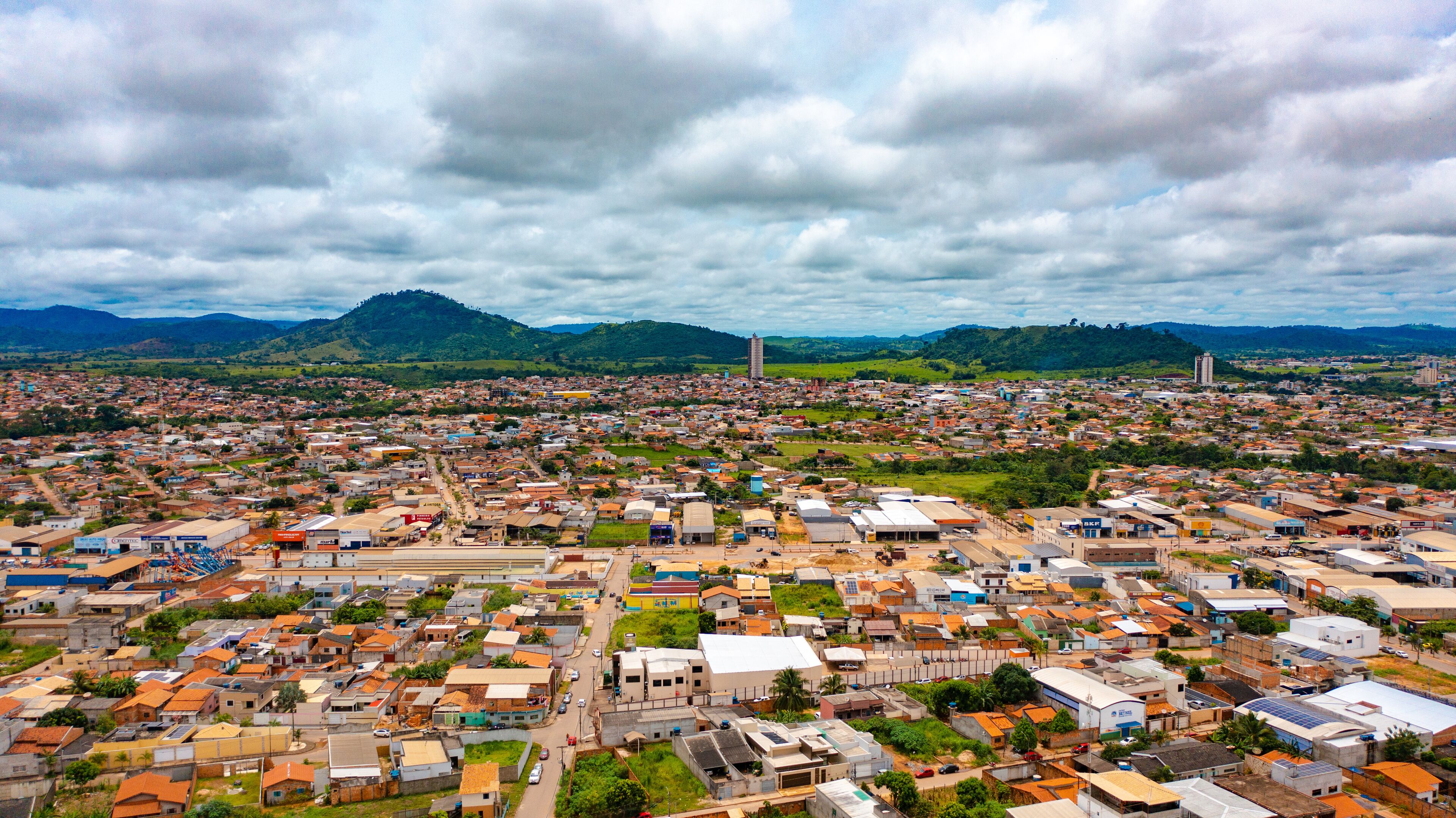 A densely populated city with a mix of residential and commercial buildings, surrounded by green hills and mountains.