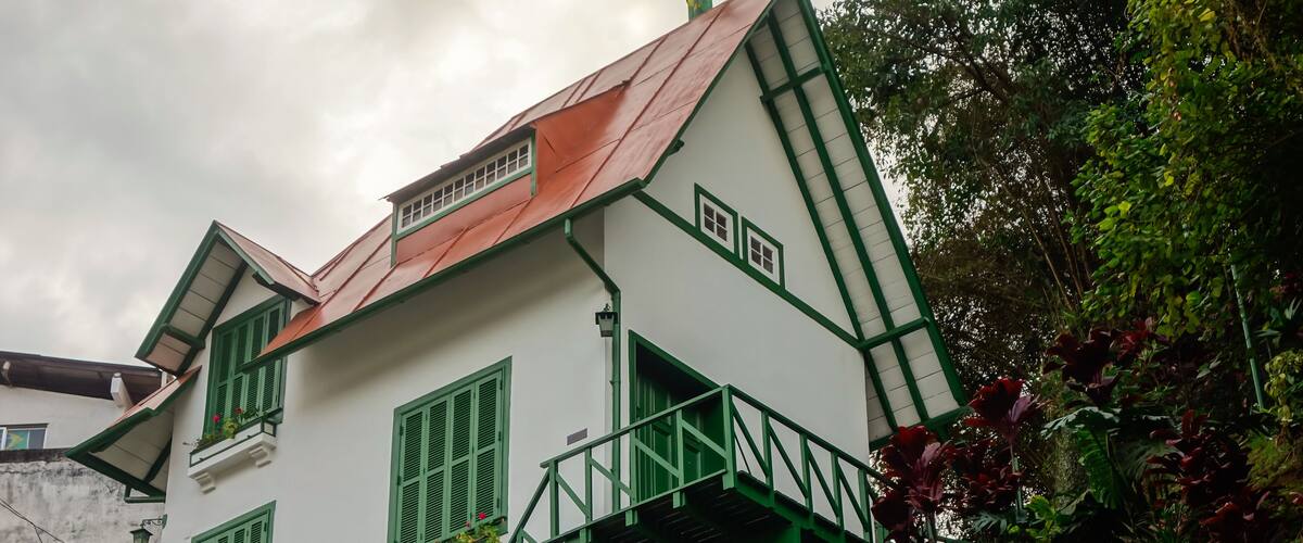 A white building with green trim and a red roof, labeled "CASA DE SANTO DOMINGO".