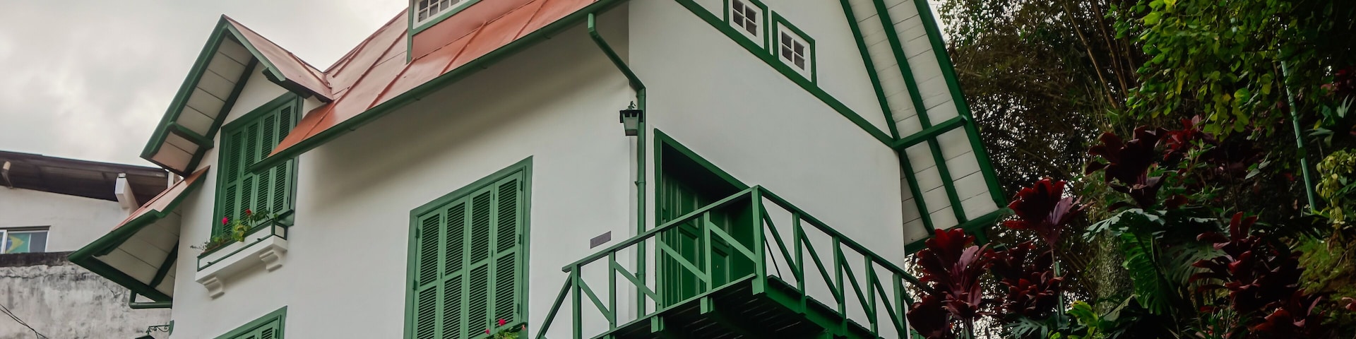 A white building with green trim and a red roof, labeled "CASA DE SANTO DOMINGO".