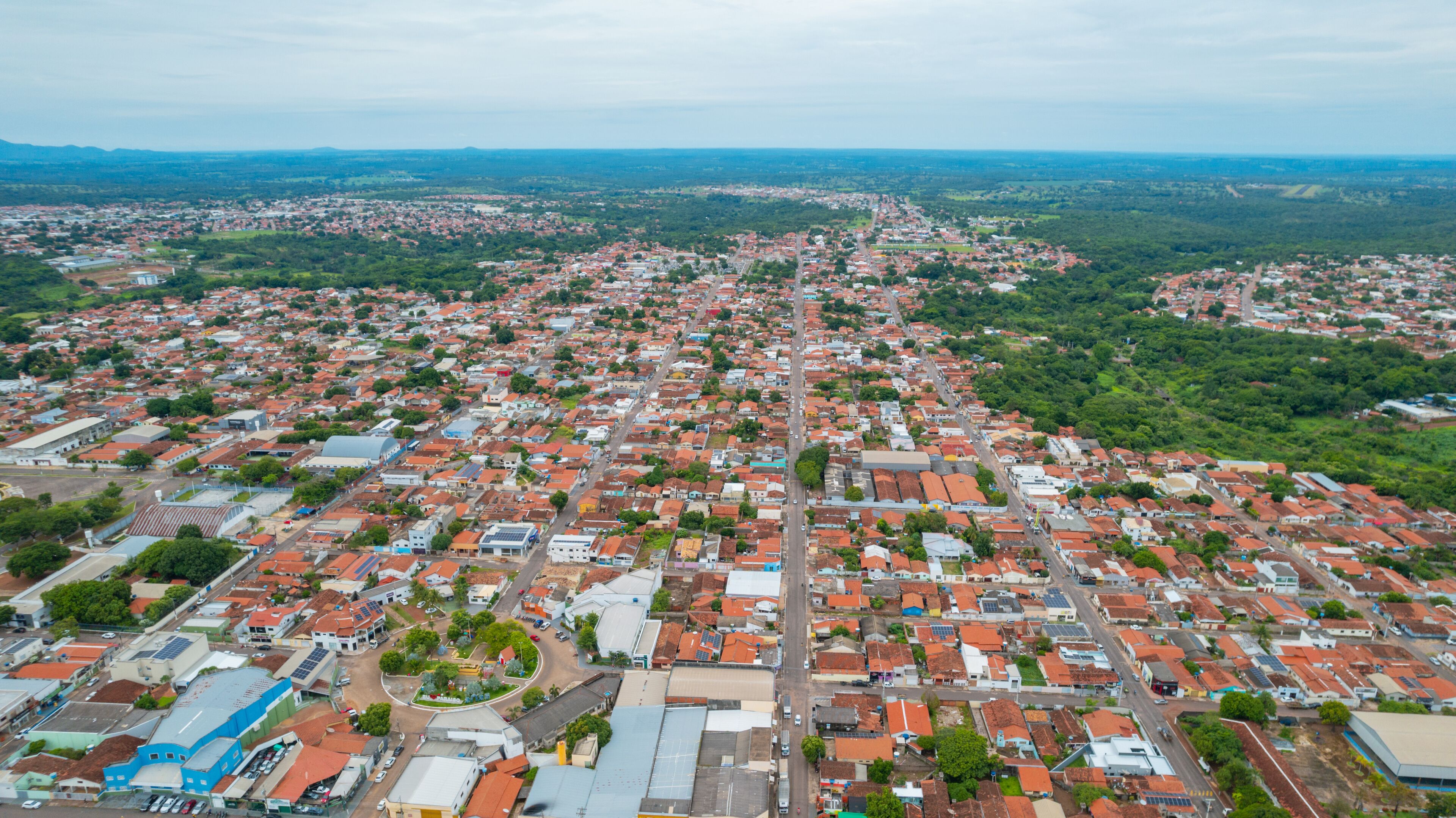 An aerial view of a densely populated urban area with red-roofed buildings and green spaces.