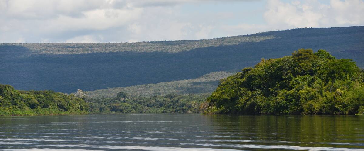 A calm lake with a forested hill in the background.