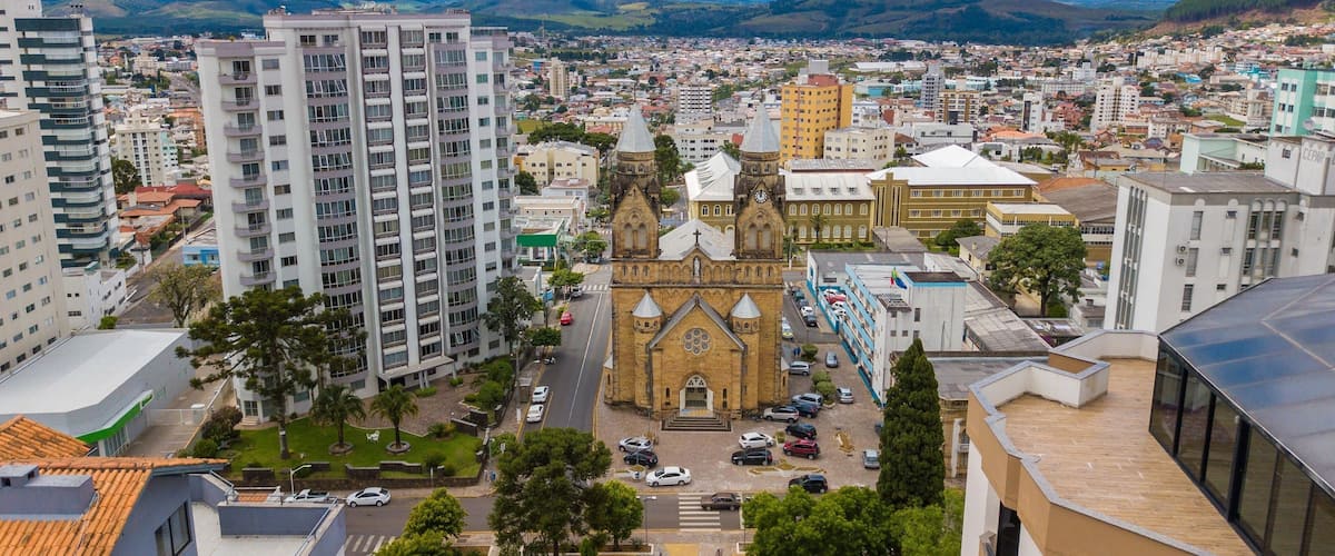 A cityscape with a prominent church, modern buildings, and a mountainous backdrop.