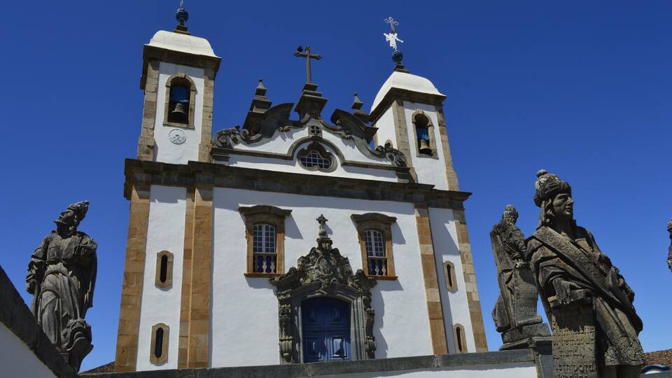 A historic church with two bell towers, a central dome, and statues of historical figures.
