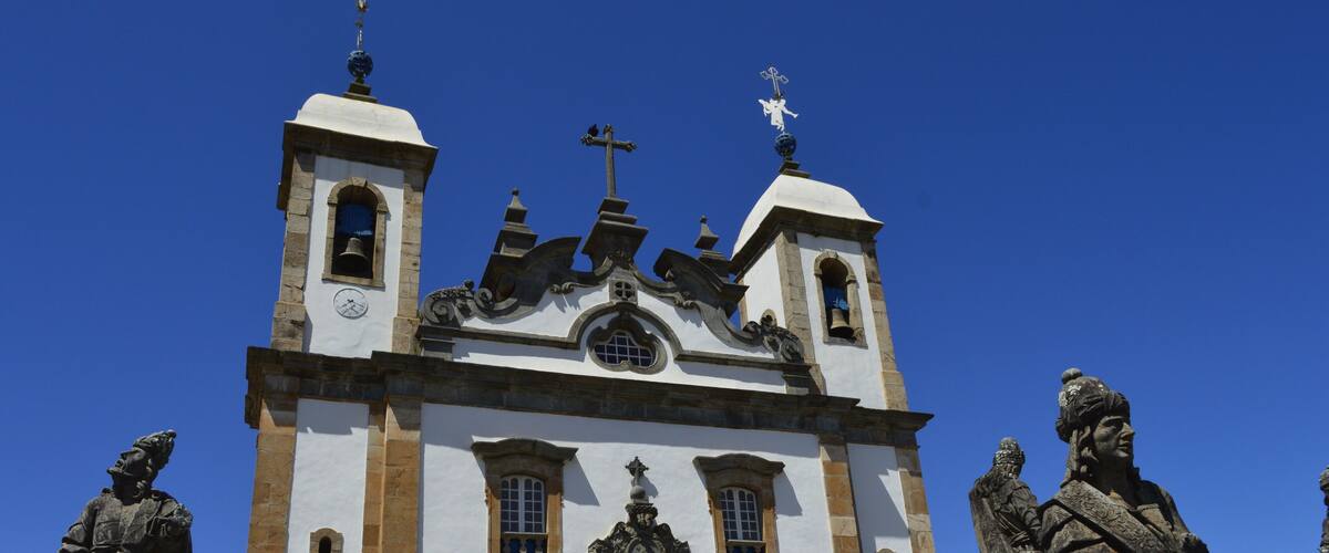 A historic church with two bell towers, a central dome, and statues of historical figures.