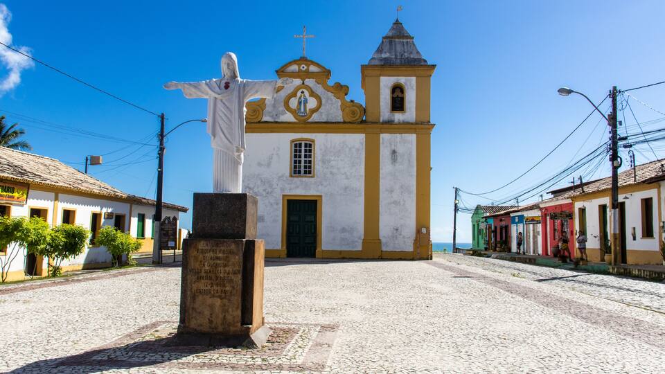 A cobblestone street leading to a church with a statue in front.