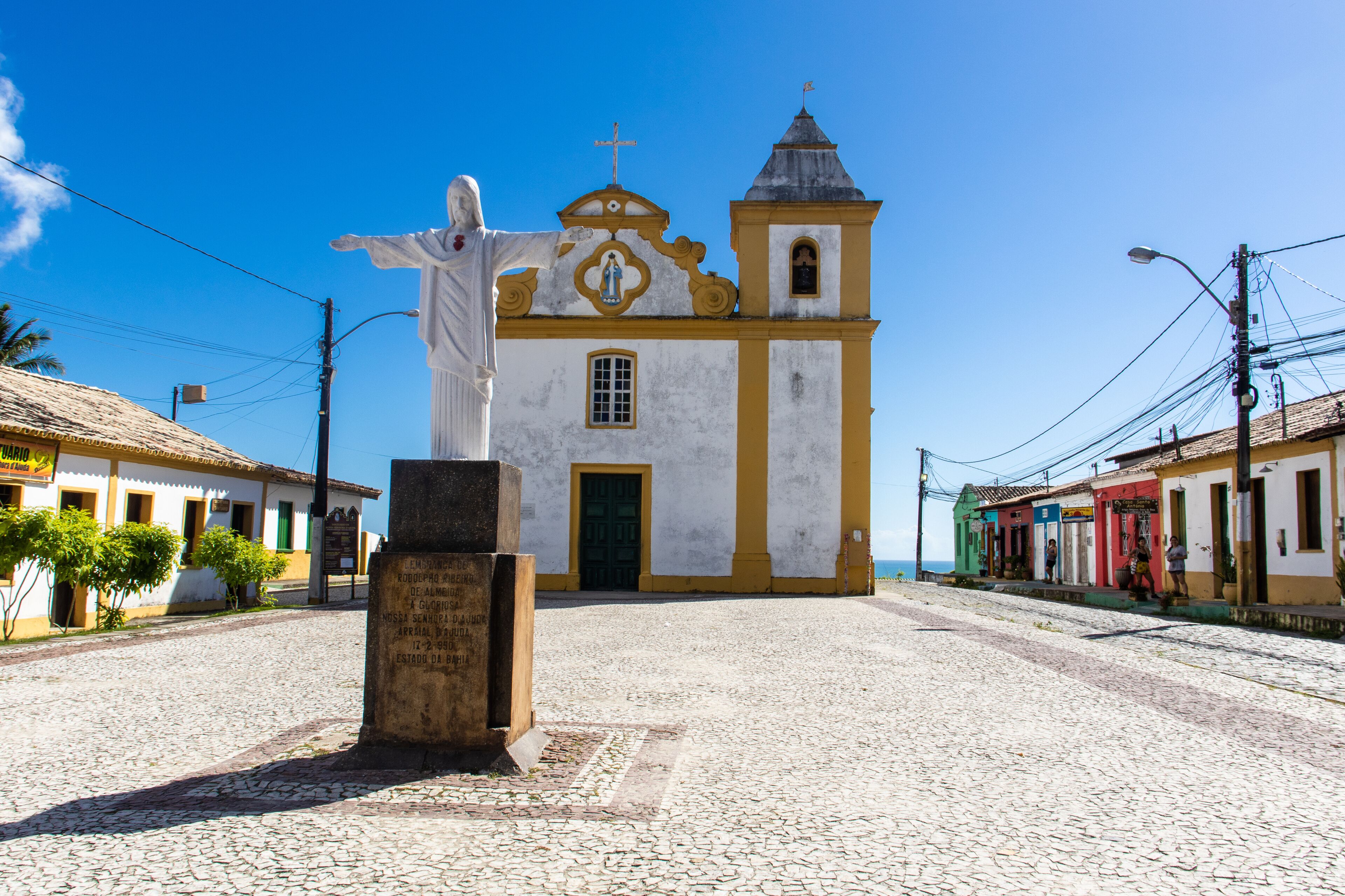 A cobblestone street leading to a church with a statue in front.