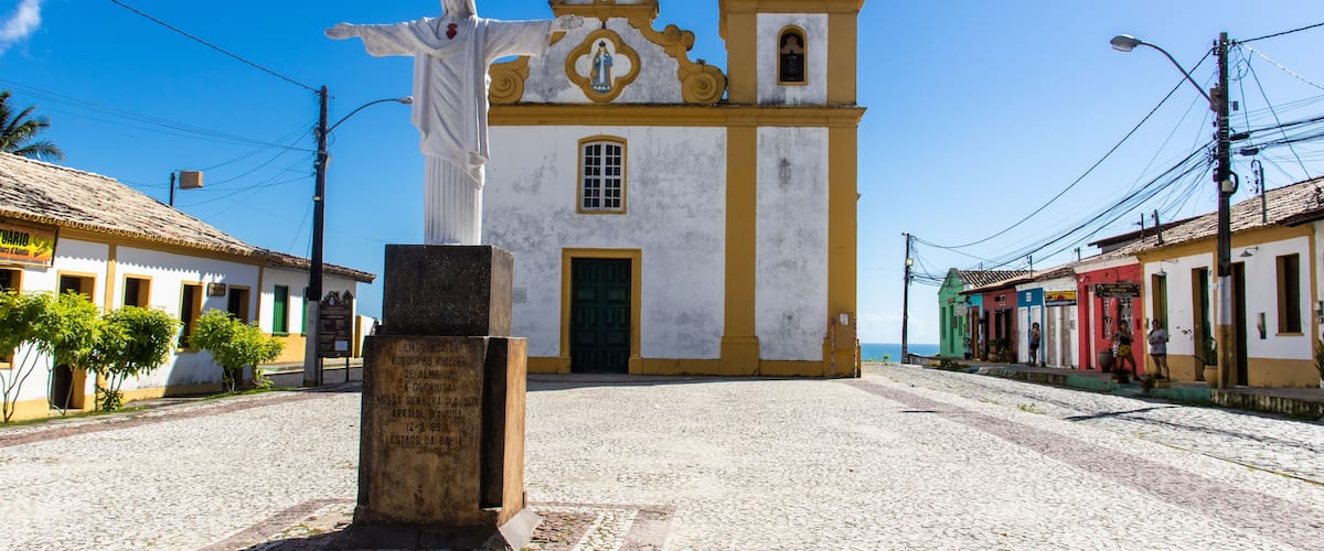 A cobblestone street leading to a church with a statue in front.